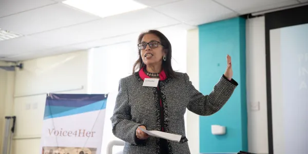 A person in a black and white blazer making a speech