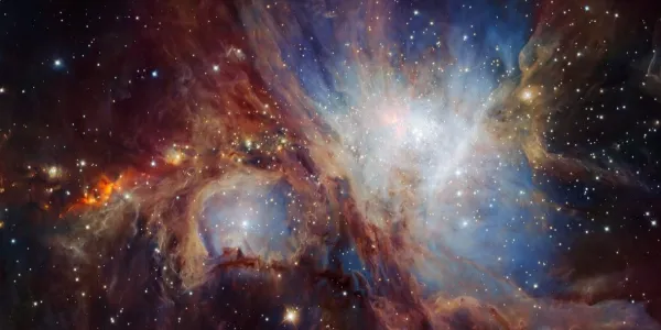The Orion Nebula. A black background with clouds of blue, red and white, and some stars.