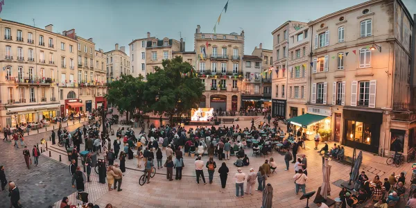 A town square featuring an outdoor cinema screen. Crowds are gathered and standing watching the screen. 