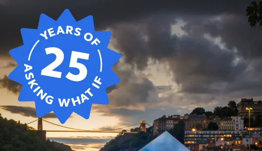 A metal cube with a lit up text that reads what next in front of a moody cityscape of Bristol and a logo that reads 25 years of asking what if in the corner