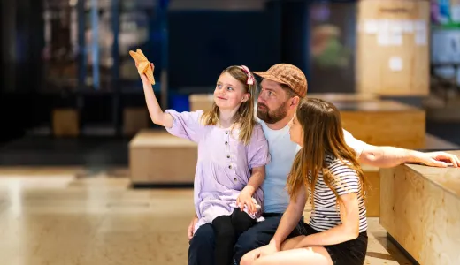 A man wearing a baseball cap and two children holding up a star shell in We The Curious