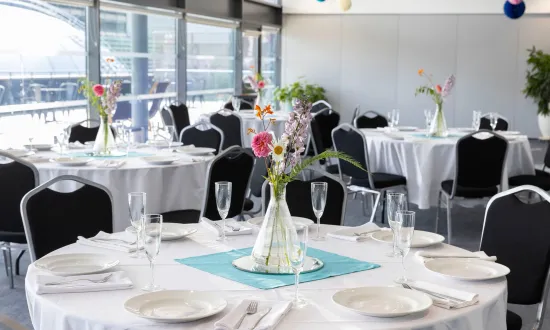 Tables dressed for a dinner party with flowers on top. 