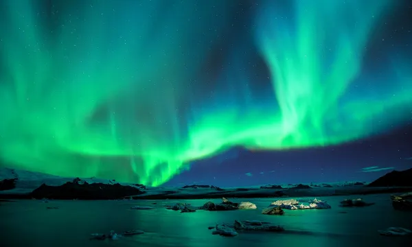 The Aurora Borealis, with blues and greens over a lake.