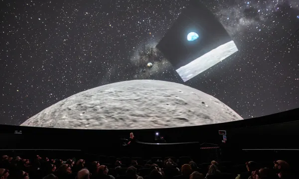 In the Planetarium at We The Curious with people in the audience looking up at the Moon and the image of 'Earthrise' the precursor to the Artemis 2 mission.