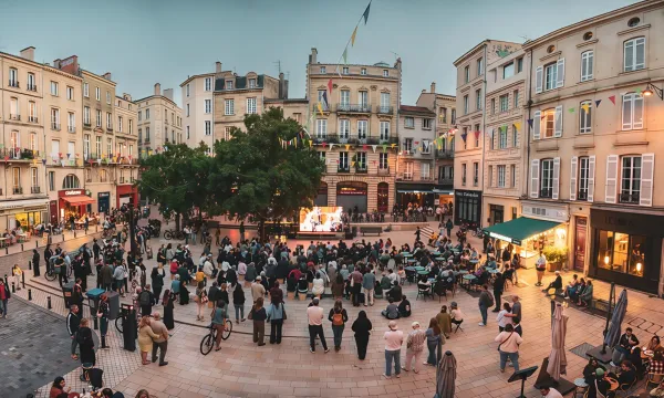 A town square featuring an outdoor cinema screen. Crowds are gathered and standing watching the screen. 