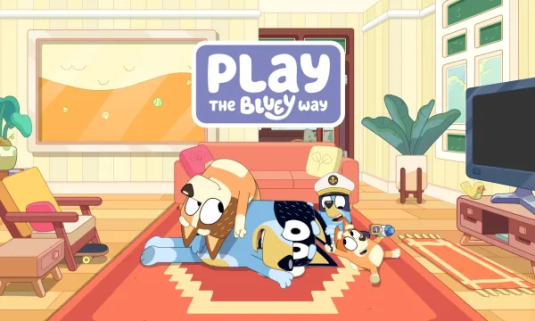 A still from the Bluey animation series. It shows a cartoon dad dog smiling being piled on top of by the rest of his family. The still carries the words 'Play the Bluey Way'