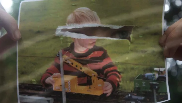 A ripped photograph of child boywith eyes showing through