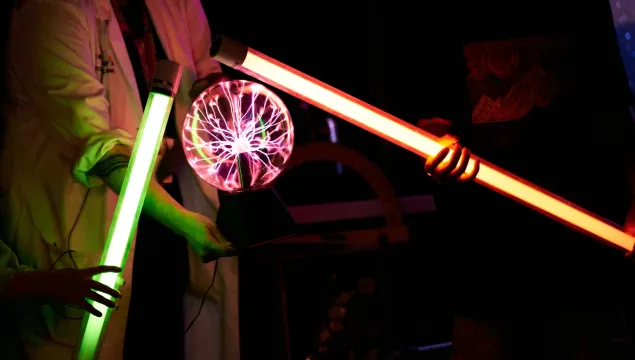 There are two light up rods touching a plasma ball in the centre of the image