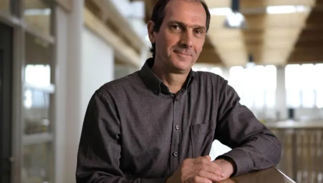 A portrait shot of a person with dark hair and a dark shirt, looking towards the camera 