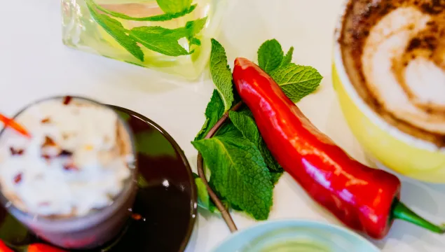 Cups of hot chocolate and minty tea with a chilli pepper and mint leaves in the middle 