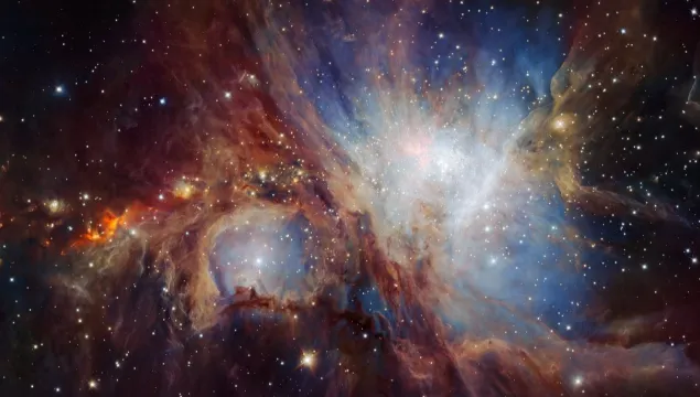 The Orion Nebula. A black background with clouds of blue, red and white, and some stars.