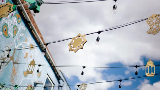 Golden Eid decorations hang from string lights strung between buildings