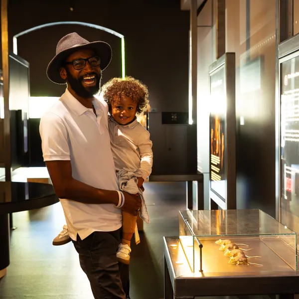 A man wearing a hat, holding a toddler laughing and smiling