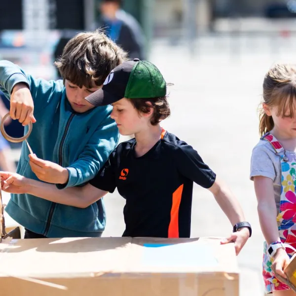 Three children building with cardboard and Sellotape on Millennium Square