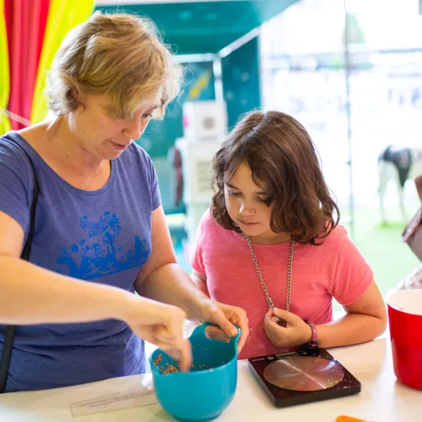 An adult and child are together in a kitchen space with a brightly coloured bowl on a white surface.