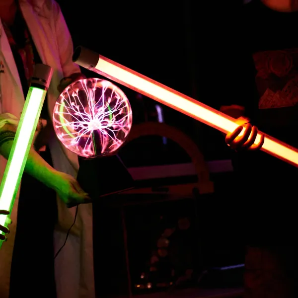 There are two light up rods touching a plasma ball in the centre of the image