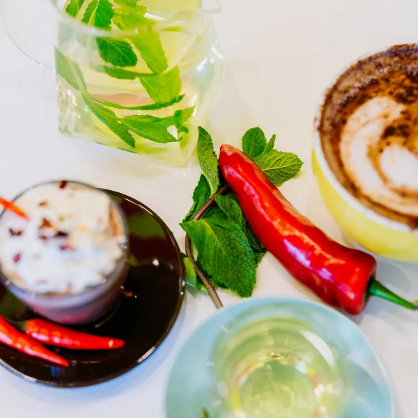 Cups of hot chocolate and minty tea with a chilli pepper and mint leaves in the middle 