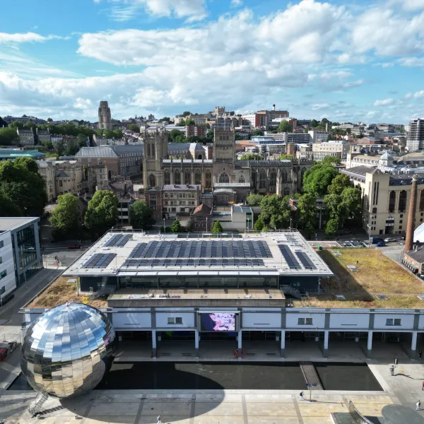 An aerial shot of the We The Curious building, with cityscape behind andwritten notes, a foam model human head and two small figurines