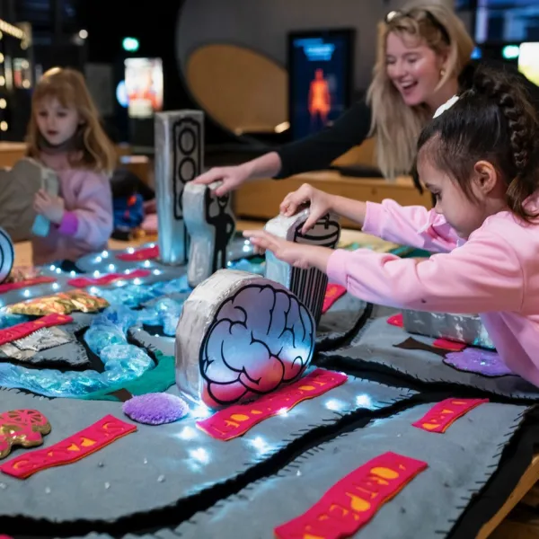 A group of people are in the middle of a science centre playing with a soft playable map.