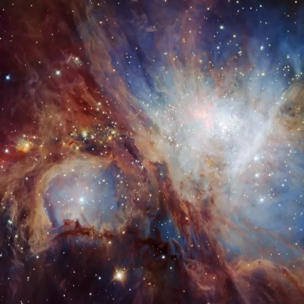 The Orion Nebula. A black background with clouds of blue, red and white, and some stars.